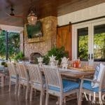 Covered patio with stone fireplace, dining table, seating area, and barn doors.