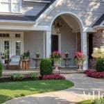 Home exterior with arched entryway, columns, double doors, and lush landscaping.