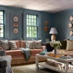 Blue wall with window, plate collection, and sofa.
