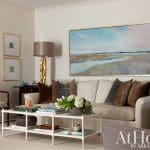 Cream sofa with gold lamps and artwork in a living room.