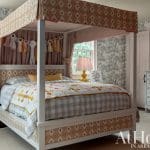 Four-poster bed with patterned wallpaper and pink bedding.