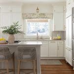 White kitchen with window, cabinetry, and seating.