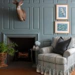 Dark teal paneling with a mounted deer head and floral prints.