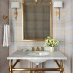 Powder room with pale blue and gold plaid walls, marble sink, and gold fixtures.