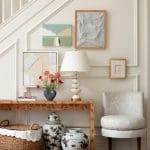 White staircase with a console table featuring artwork and decorative objects.