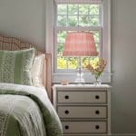 Bedside table with striped bedding and a floral lampshade.