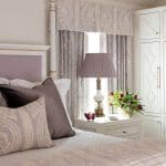 Purple bedroom with patterned drapes and a bedside table.
