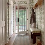 Hallway with green wallpaper, bench, and exterior doors.