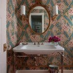 Blue and floral patterned wall, gold mirror, and vanity.