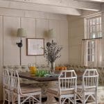 White dining area with patterned banquette seating and wicker chairs.