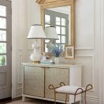 Gold-framed mirror, lamps, and console table in a hallway.