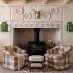 Cream-colored room with plaid chairs, fireplace, and decorative plates.