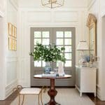 Entryway with paneled walls, gray doors, and a floral arrangement.