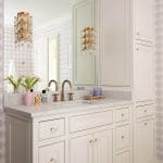 White vanity with marble countertop and brass fixtures.