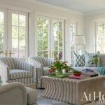 White sitting room with patterned sofa, armchair, and coffee table.