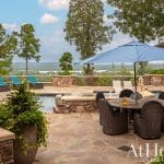 Outdoor patio with pool, furniture, and a blue umbrella.