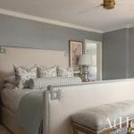 Neutral bedroom with a large upholstered headboard and patterned bedding.