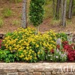 Stone retaining wall with colorful flower beds in Arkansas.