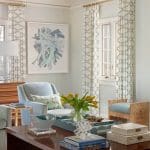 Blue and white patterned drapes, gray sofa, and coffee table with books.