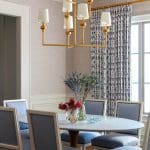 Gold chandelier, blue patterned curtains, and a dining table.