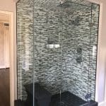Black and gray mosaic tile shower surround with glass enclosure.