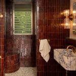 Red brick tile shower with marble bench and fixtures.