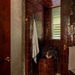 Dark brown brick tile shower with a towel and plant.
