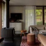 Dark wood stove, white console, and layered textiles in a living room.