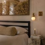 Bedroom with textured wall art, bedside table, and layered bedding.