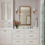 White cabinetry with gold accents and a mirror in a bathroom.