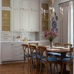 Gray kitchen cabinets with gold accents and a chandelier.
