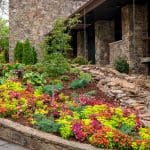 Stone house with colorful flower beds and landscaping.