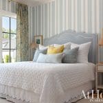 Blue and white striped bedroom with a tufted headboard and layered pillows.