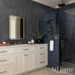 Dark blue tile bathroom with gold fixtures and mirror.
