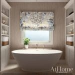 Large beige bathroom with a freestanding tub, window, and patterned roman shade.