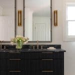 Black vanity with marble countertop and gold fixtures.