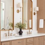 Wooden vanity with gold sconces and mirror in a bathroom.