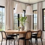 Dining area with a wooden table, cane chairs, and large pendant lights.