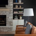 Dark gray wall with stone fireplace and built-in shelves.