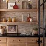 Wood shelving unit with tile backsplash and brass sconces.