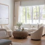 Cream sofa and chairs with a woven coffee table in a light-filled room.