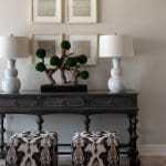 Dark console table with patterned stools and artwork.