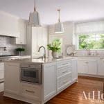 White kitchen with marble island and brass hardware.
