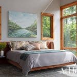 Bedroom with wooden window frames, a large painting, and a gray bed.
