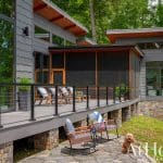 Modern home with a stone deck and metal railings.