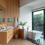 Wooden wall and bathroom with a freestanding tub and large window.