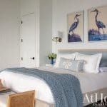 White brick wall, blue bedding, and framed heron artwork in a bedroom.