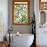 White soaking tub with wooden accents and a window.