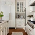 White kitchen with marble countertops, gold hardware, and white cabinetry.
