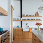 Wood kitchen with white tile backsplash, stainless steel sink, and orange flowers.